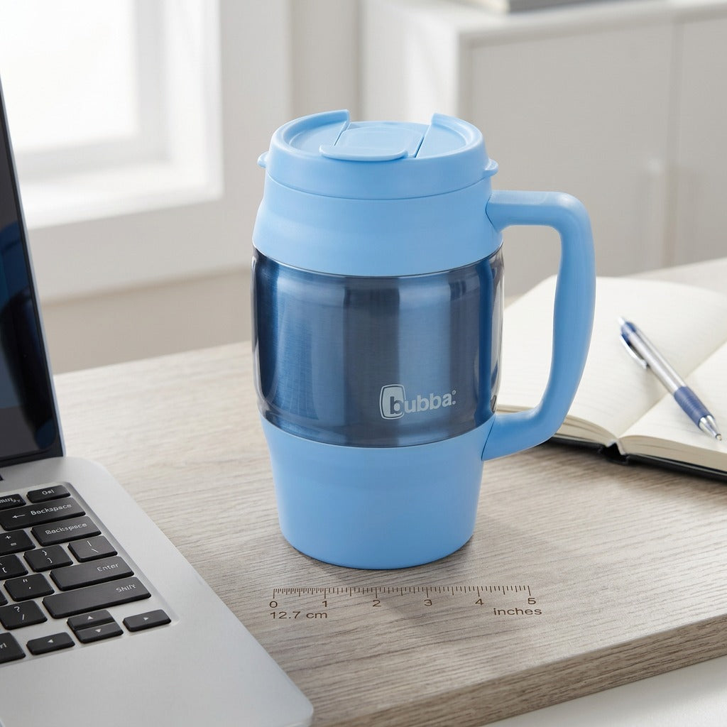 Scale view of the light blue bubba Classic 34 oz insulated mug on a desk beside a laptop and notebook.