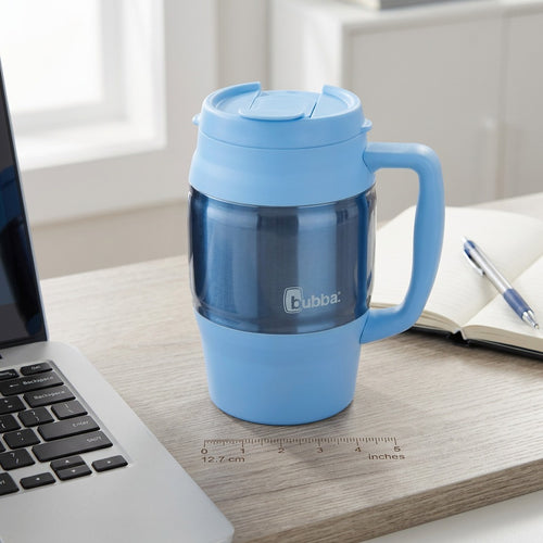 Scale view of the light blue bubba Classic 34 oz insulated mug on a desk beside a laptop and notebook.